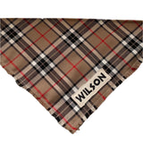 A tartan dog bandana with fringed edges, personalized with a name machine embroidered on the lower corner.