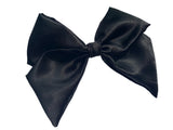 A black satin hair bow clip displayed on a white background, with a silver-colored barrette clip attached.
