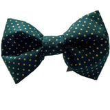 A green dog bow tie with gold polka dots laid out flat on a white background.