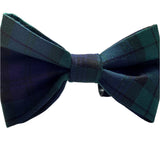 A handmade navy tartan dog bow tie laid out on a flat surface.