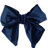 A navy blue velvet hair bow clip with a silver-colored barrette clip attached, displayed on a white background.