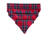 A red tartan slip on collar design dog bandana displayed on a flat surface.