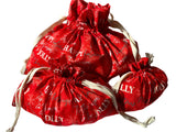 A set of red reusable drawstring Christmas gift bags with white text and design patterns. Sold separately.