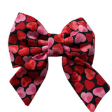 A red and pink heart-patterned dog bow tie with a slip-on design.