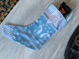A blue and white holiday stocking filled with snacks, resting on a light gray marble surface.