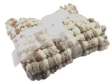 A folded chunky pom pom pram blanket cover with a textured bobble pattern in cream, beige, and light brown, wrapped with a white ribbon.