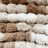 Close-up of a textured pom pom wool in  beige, brown, and white.