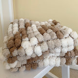 Textured blanket with brown, beige, and white colors draped over a white chair.