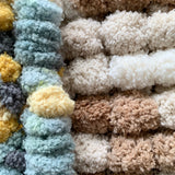 Close-up of pom pom yarn in green and brown colours.