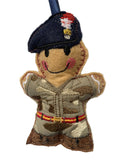 A small embroidered fabric soldier ornament with a dark blue beret, camouflage uniform, and red and yellow accents, shown against a plain light background.
