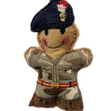 A small embroidered felt soldier ornament hanging from a blue ribbon. The character wears a dark navy beret with red, white, and gold embroidery, a tan camouflage uniform, and brown boots, with a stitched smile and pink cheeks, against a plain white background.