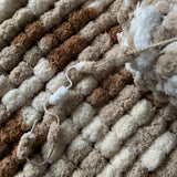 Close-up of textured yarn in beige, brown, and white colors for size comparison.