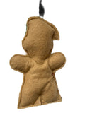 A handmade felt gingerbread person ornament or hanging decoration in a warm tan color, featuring a black hanging ribbon at the top, shown against a plain white background.
