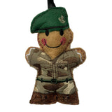 A small embroidered felt soldier ornament wearing a green beret and camouflage uniform, hanging from a black ribbon on a plain light background.