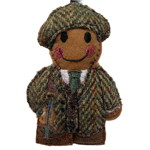 A handcrafted felt gingerbread man ornament in a traditional tweed outfit, with a smile on its face, designed as a hunter/gamekeeper.