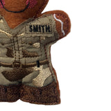 Close-up of a gingerbread decoration with 'SMITH' embroidered on its chest against a white background