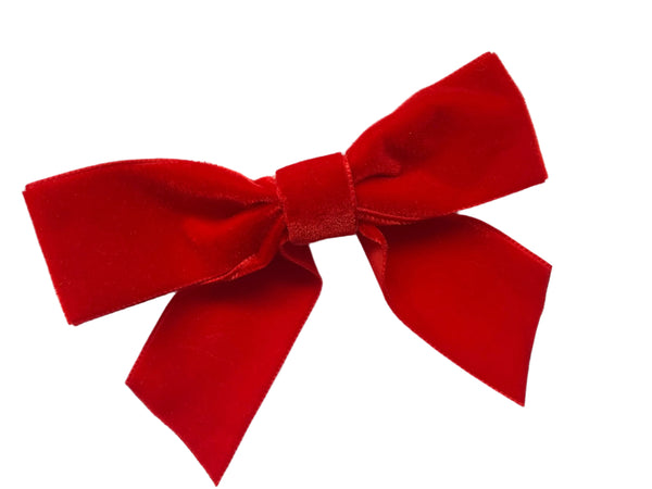 A small red velvet hair bow clip laid out on a white surface.