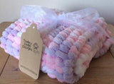 Pram baby blanket in shades of pink, purple and white. This chunky knit baby blanket cover is hand knitted in a super soft  pom pom wool.