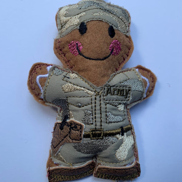 Soldier felt gingerbread decoration. Dressed in cotton fabric embroidered uniform. With faux leather brown boots, cap and sidearm in faux leather holster.