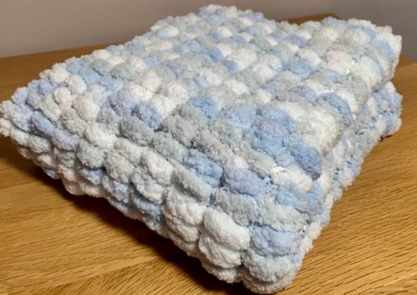 Blue, grey and white, hand knitted pom pom wool pram cover.