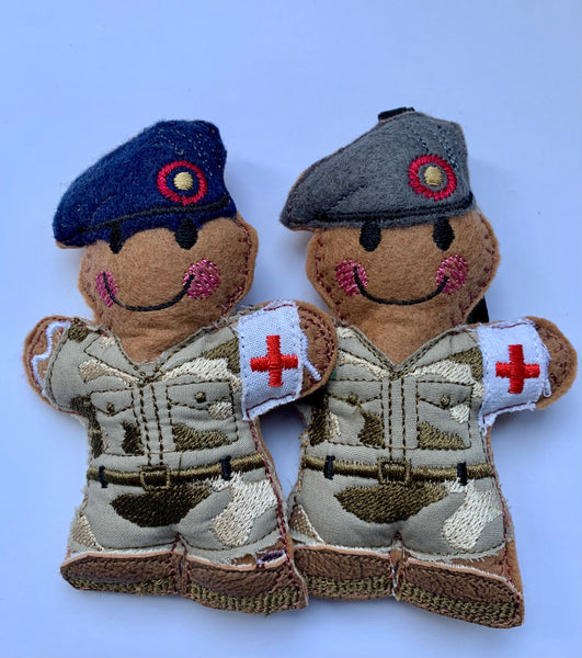 Army medic felt gingerbread soldier decoration.  In embroidered fabric camouflage uniform, faux leather brown boots, white armband with red cross. Navy or grey beret.