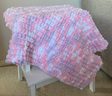 Large pink, purple and white baby blanket hand knitted in a chunky super soft pom pom yarn.