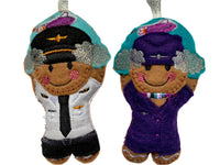 Pilot and cabin crew felt gingerbread decorations with clouds and airplane. On white background.
