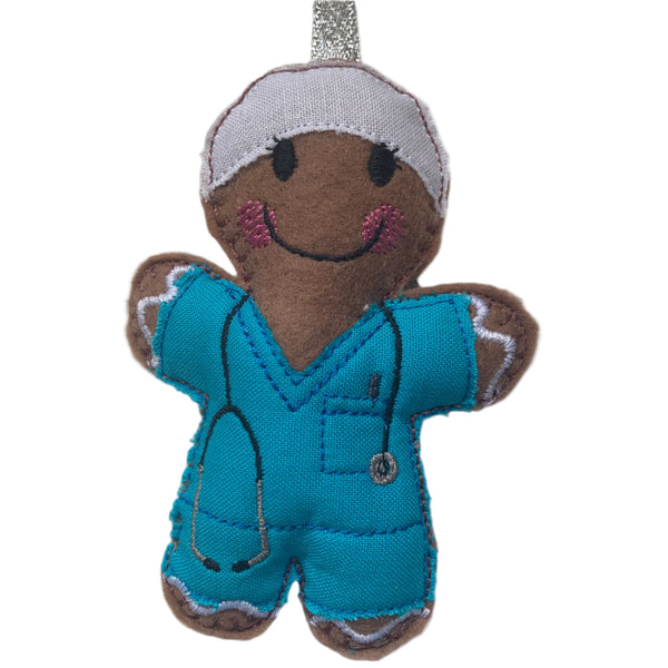 gingerbread man wearing turquoise scrubs and white hat, designed as a medical doctor Christmas decoration, hanging from a silver ribbon.