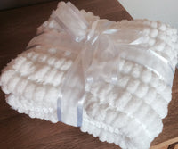 Pram baby blanket in a traditional white. This chunky knit baby blanket cover is hand knitted in a super soft  pom pom wool.