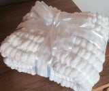 Pram baby blanket in a traditional white. This chunky knit baby blanket cover is hand knitted in a super soft  pom pom wool.