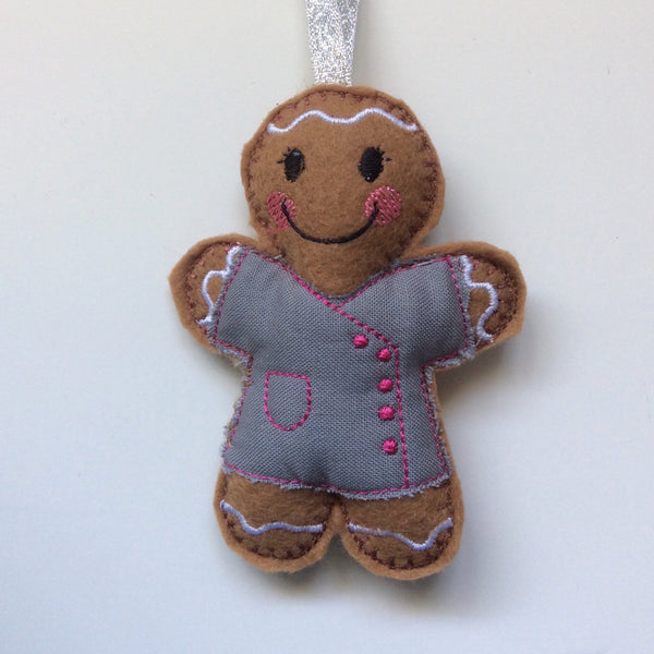 Beautician felt gingerbread decoration. Dressed in grey cotton tunic with pink buttons and decorative finish. Lightly filled with a polyester filling to create depth and character. Hand sewn to finish.