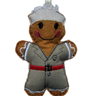 A gingerbread  decoration in a traditional military nurses uniform featuring a brown body with a grey and red uniform, and a smiling face.