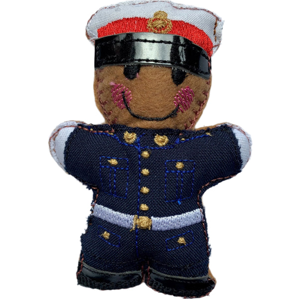 A handmade and machine-embroidered gingerbread man in a Royal Marine military dress uniform, primarily in navy and white colors with red brim on the hat, designed to be a Christmas decoration.