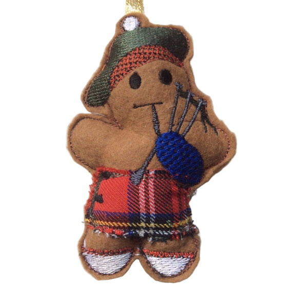 Scottish piper gingerbread man decoration in red tartan kilt. Displayed on white background.