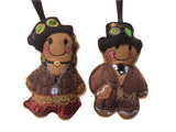 Two felt gingerbread man and woman decorations in steampunk fashion, with decorative details such as hats and chains, designed as ornaments.