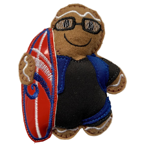 Surfer Boy Gingerbread Man Decoration. Dressed in black wetsuit with blue detail, holding a red surfboard. Displayed on white background.