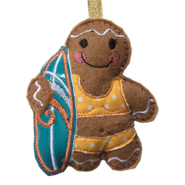 Gingerbread girl decoration in a yellow polka-dot bikini. Holding a surfboard, intended as a Christmas decoration.